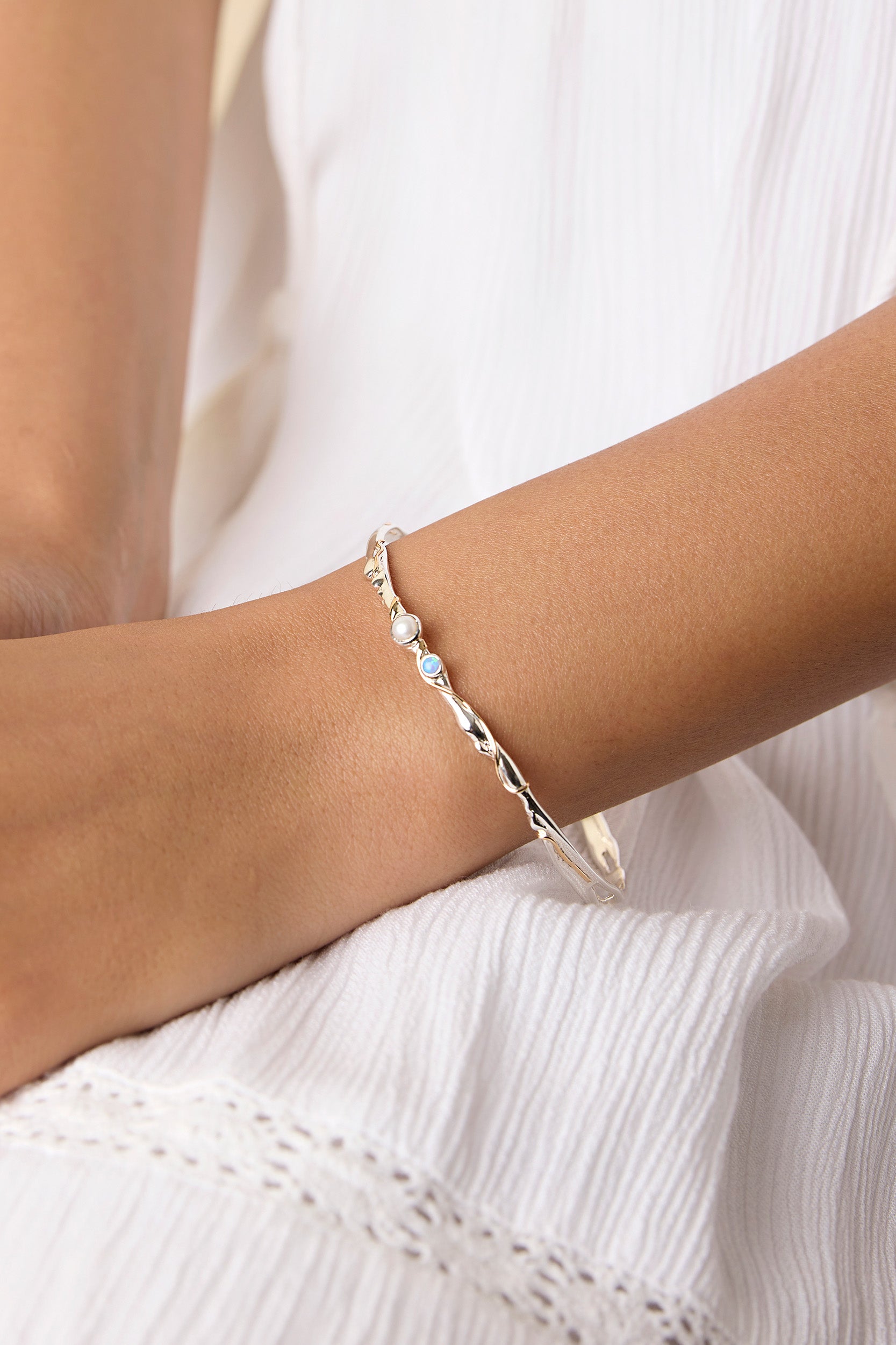 model wearing a delicate silver bracelet adorned with opal and pearl