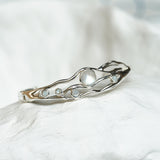 sterling silver flowing bangle with round moonstones on a white ceramic