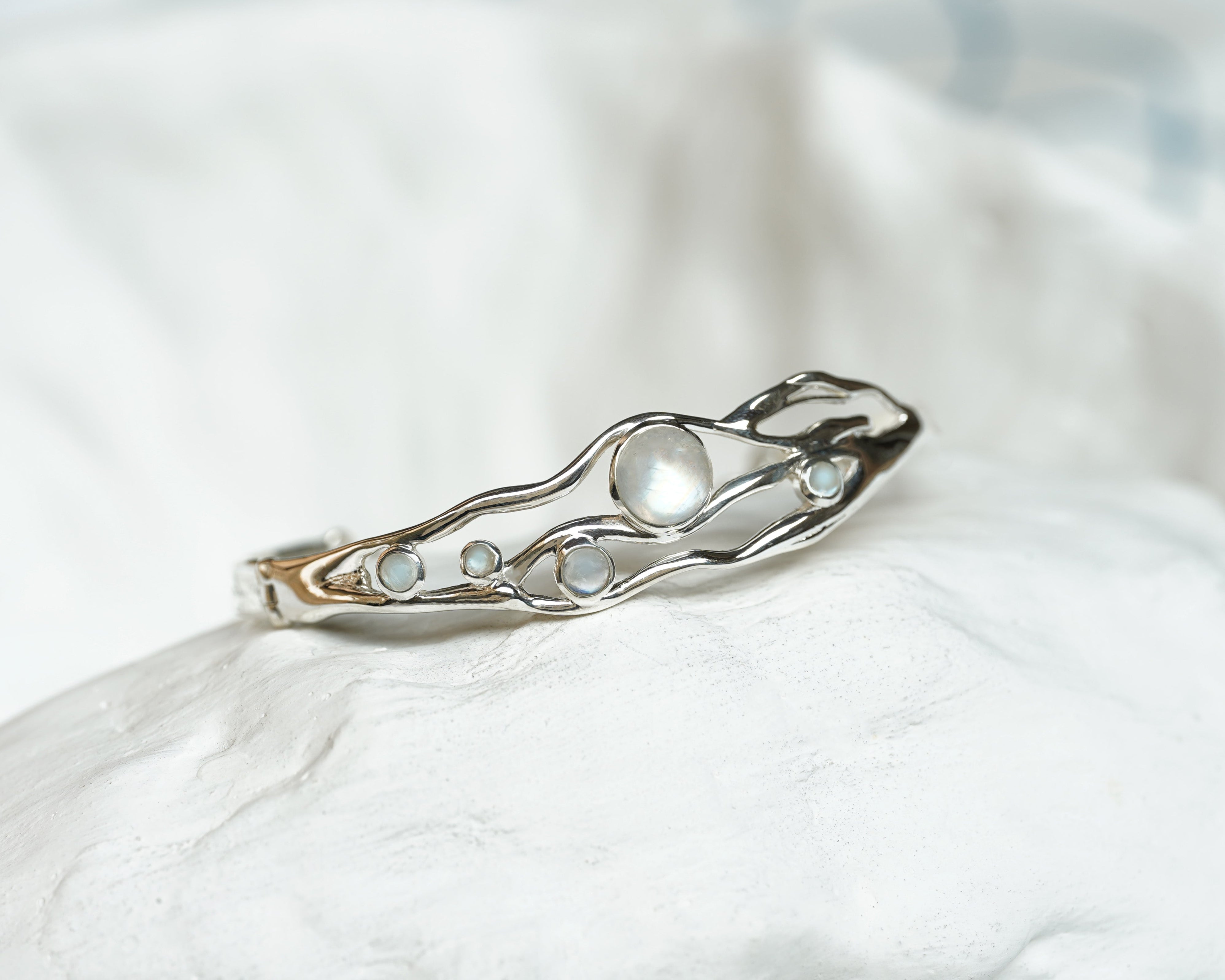 sterling silver flowing bangle with round moonstones on a white ceramic