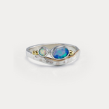A Sterling Silver ring with a central blue-green Opal and white Opal accents, featuring gold flowing details on a hammered band.