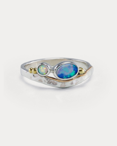 A Sterling Silver ring with a central blue-green Opal and white Opal accents, featuring gold flowing details on a hammered band.