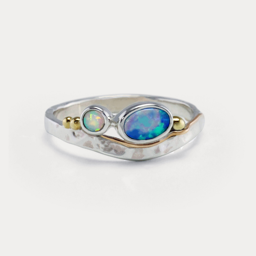 A Sterling Silver ring with a central blue-green Opal and white Opal accents, featuring gold flowing details on a hammered band.