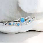 a flowing opal bracelet made in sterling silver nestled among white petals.