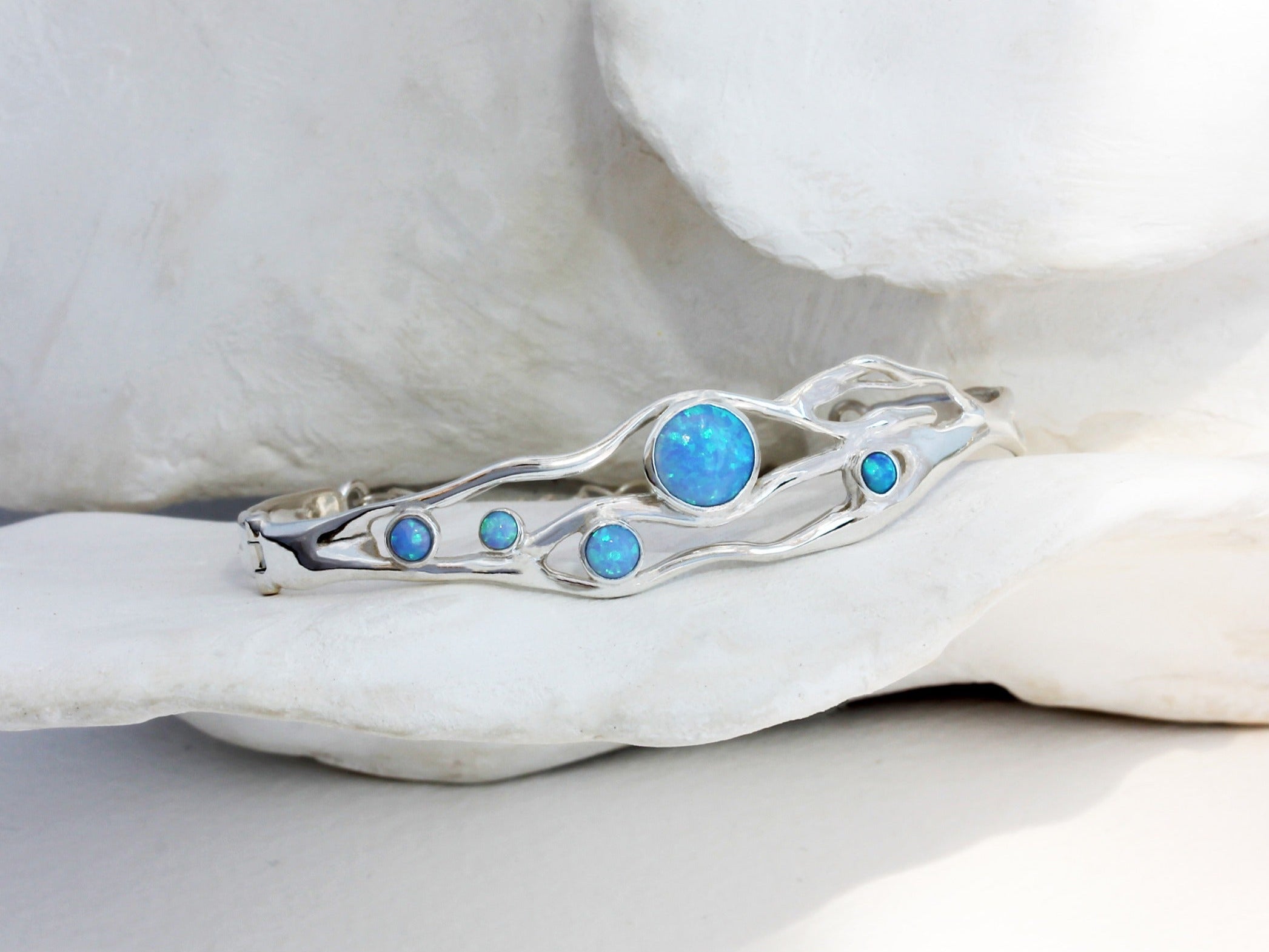 a flowing opal bracelet made in sterling silver nestled among white petals.