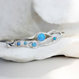 a flowing opal bracelet made in sterling silver nestled among white petals.
