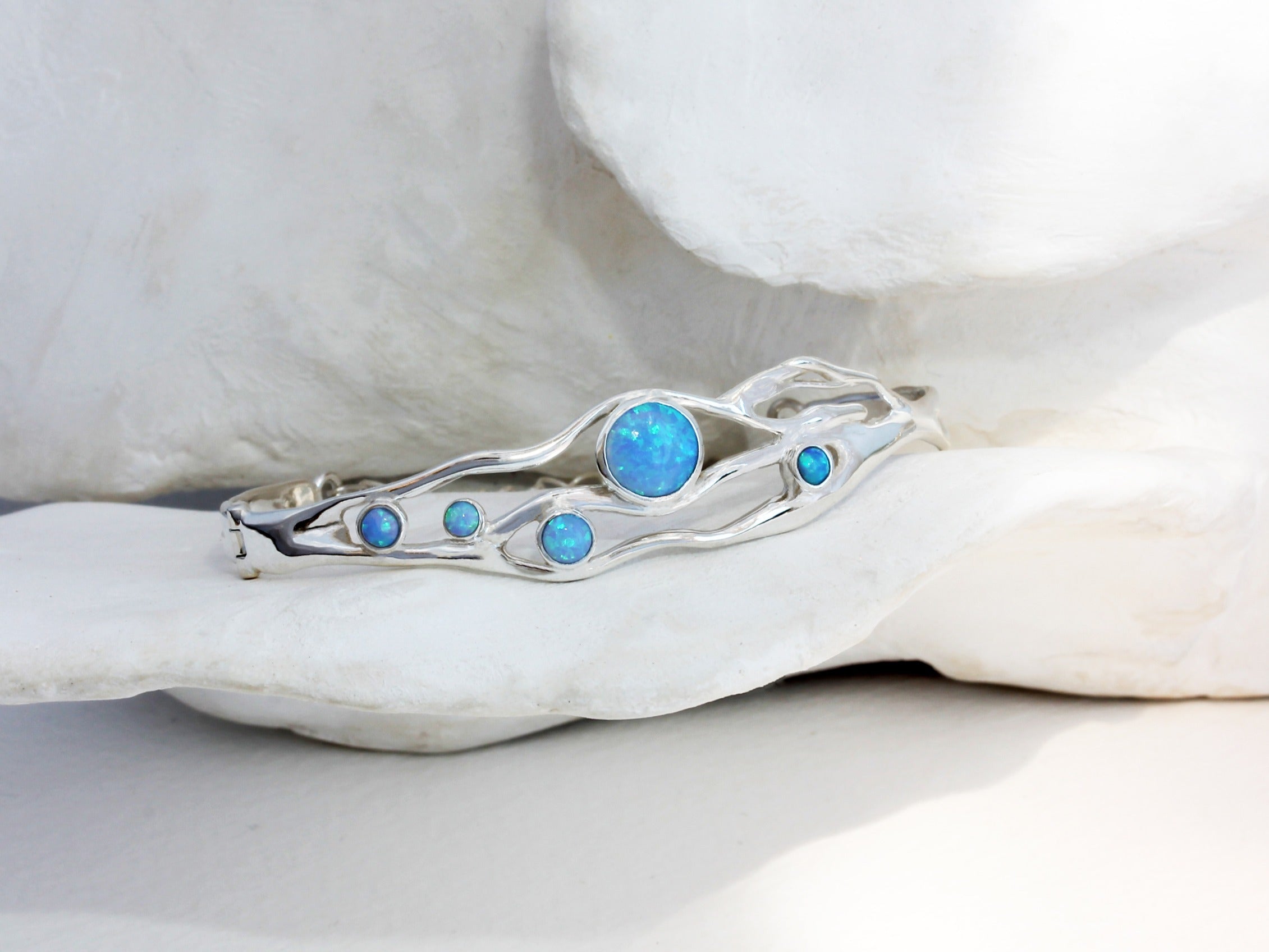 a flowing opal bracelet made in sterling silver nestled among white petals.