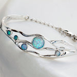 Sterling Silver bracelet with five round Opal stones on a grey textured background