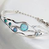 Sterling Silver bracelet with five round Opal stones on a grey textured background