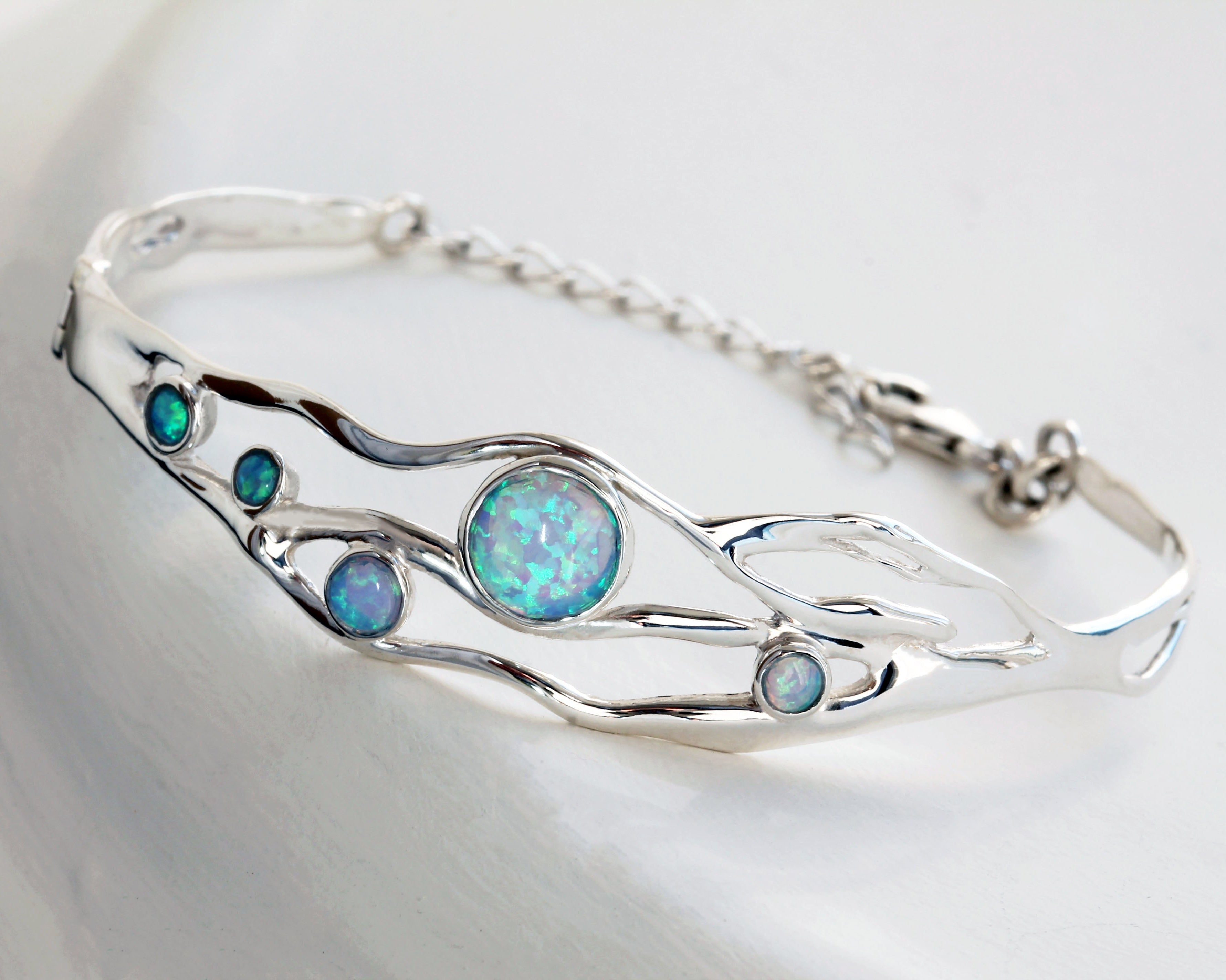 Sterling Silver bracelet with five round Opal stones on a grey textured background