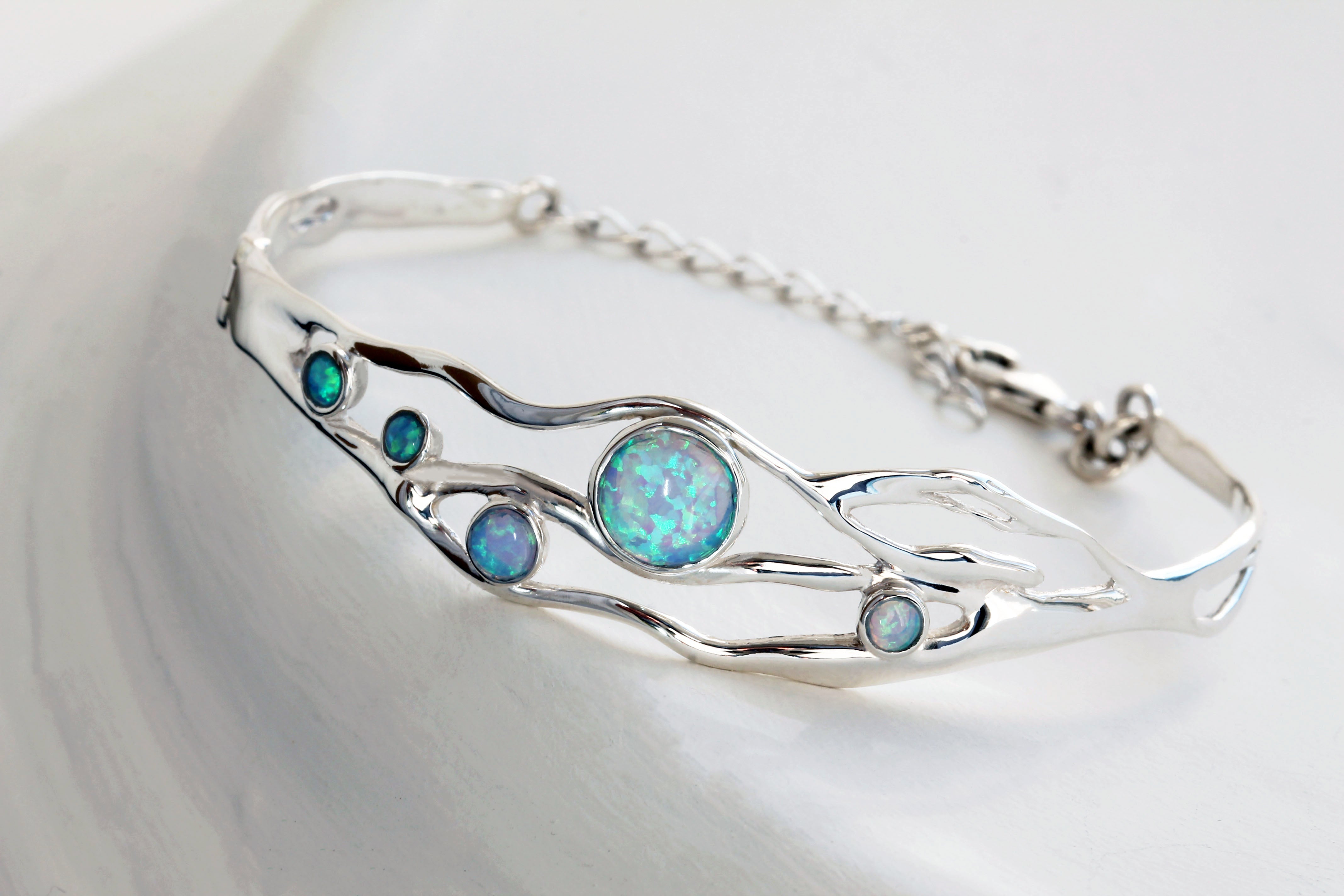 Sterling Silver bracelet with five round Opal stones on a grey textured background