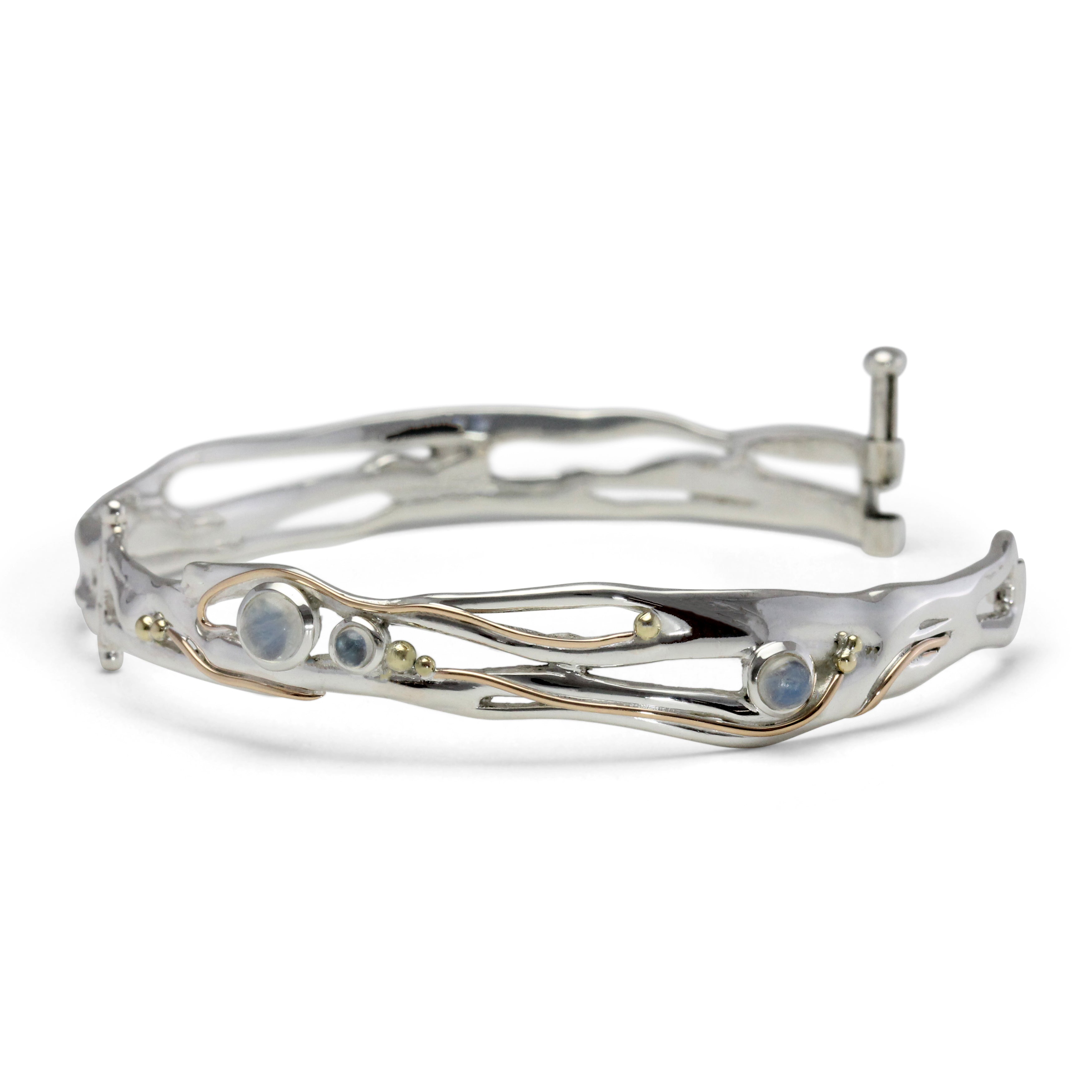 A hinged bangle adorned with moonstone and gold details on a white background