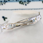 Silver bracelet with gemstones against a floral-patterned background