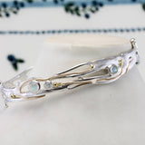 Silver bracelet with gemstones against a floral-patterned background