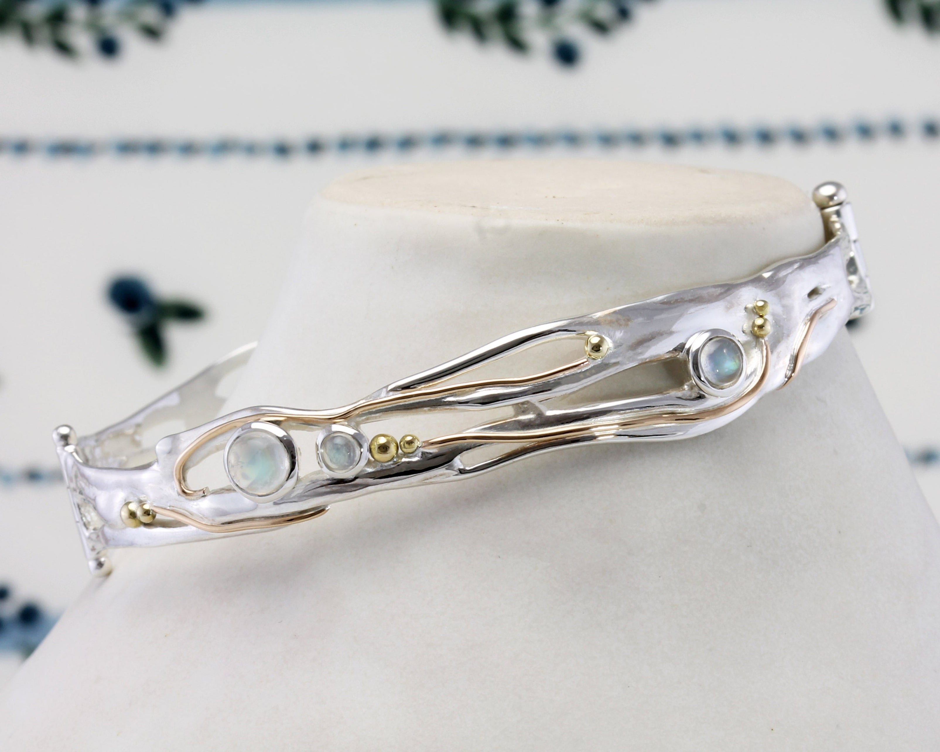 Silver bracelet with gemstones against a floral-patterned background