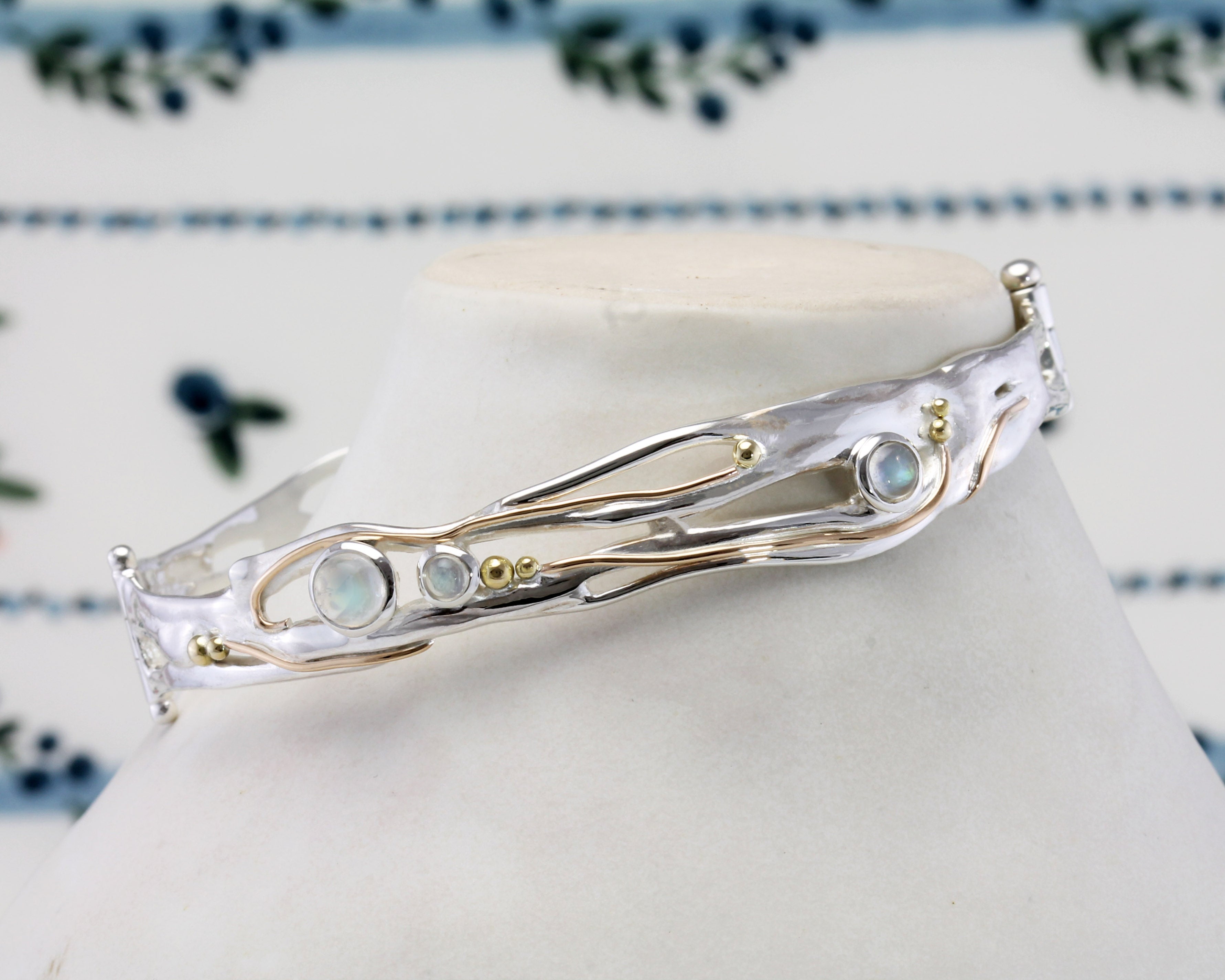 Silver bracelet with gemstones against a floral-patterned background